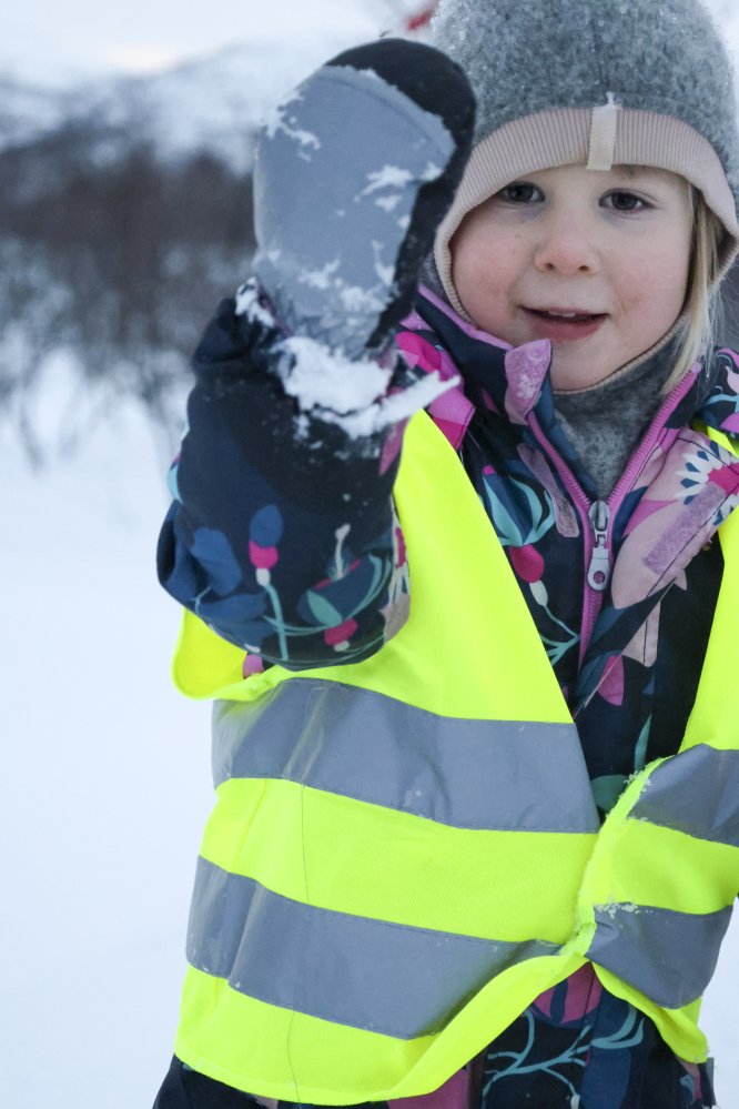 Lapsi talvihaalarissa esittelee hanskallaan olevaa ötökkää iloisena