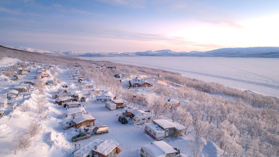 Caravan-alue Kilpisjärvellä kuvattuna ylhäältäpäin ja maisemaa Kilpisjärvelle kaamospäivän pastellinsävyisessä valossa.